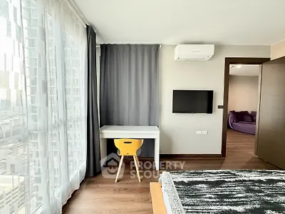 Modern bedroom with city view, featuring a cozy workspace and stylish decor.