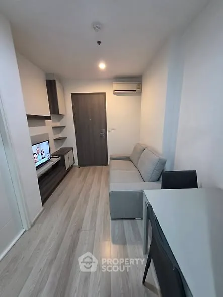 Modern living room with sleek furniture and wall-mounted TV in a cozy apartment.