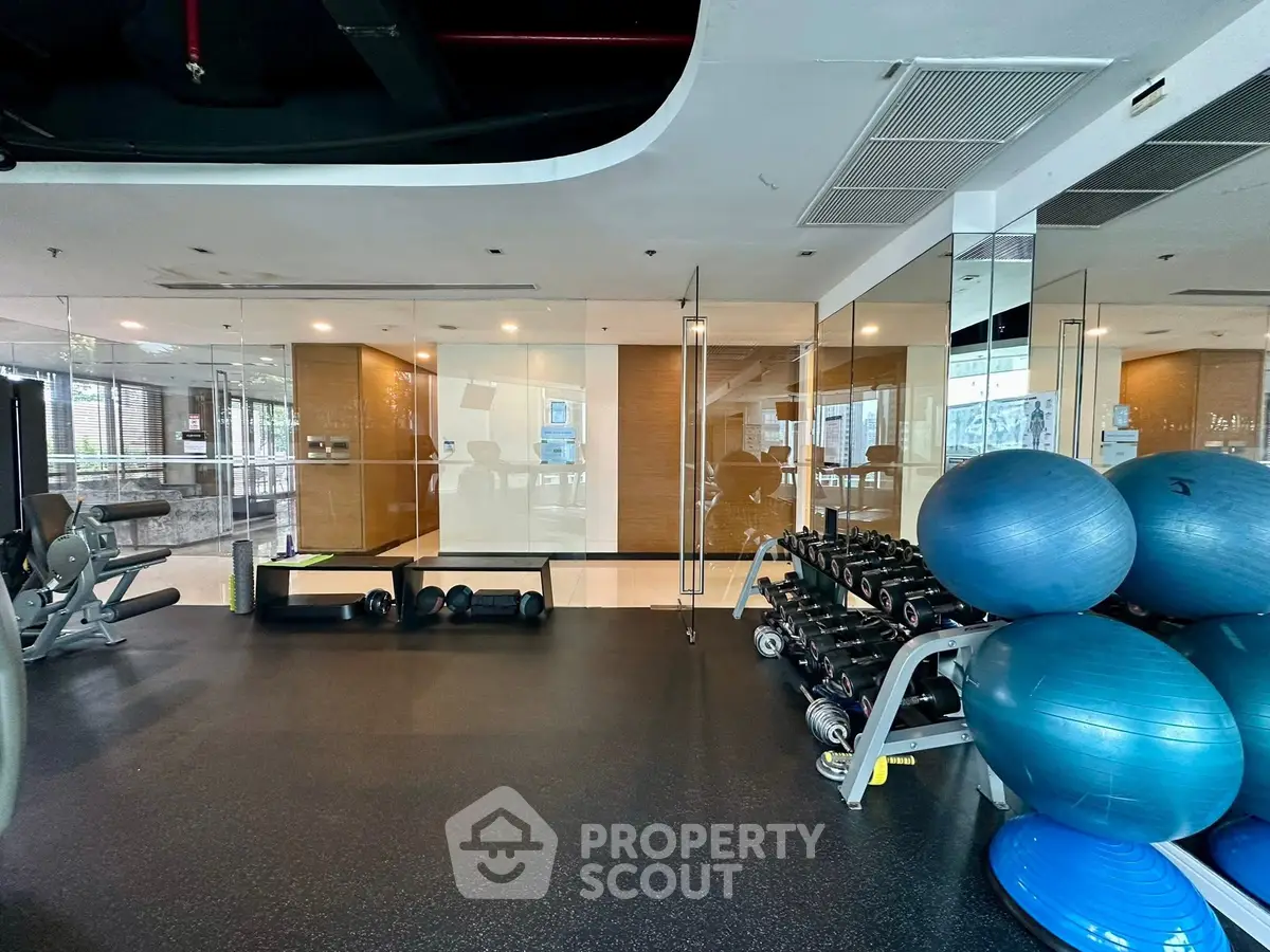 Modern gym with state-of-the-art equipment and spacious workout area in luxury building.