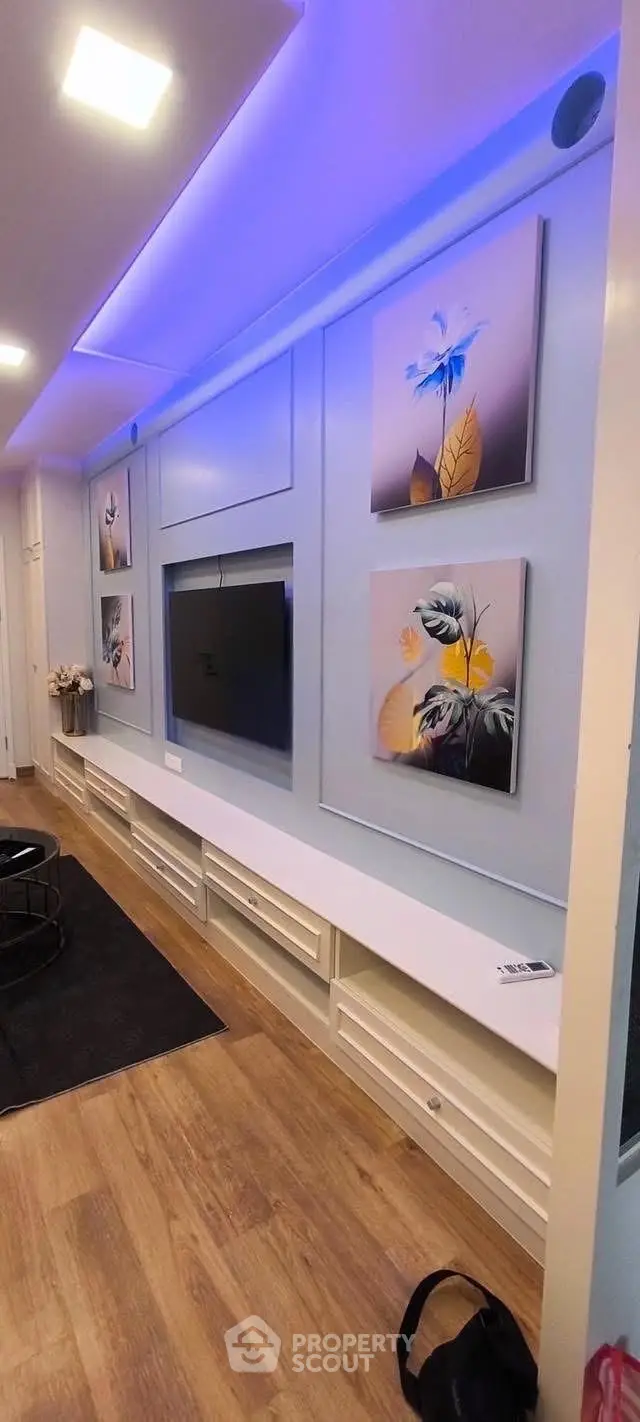Modern living room with stylish wall art and sleek TV setup, featuring ambient lighting and wooden flooring.