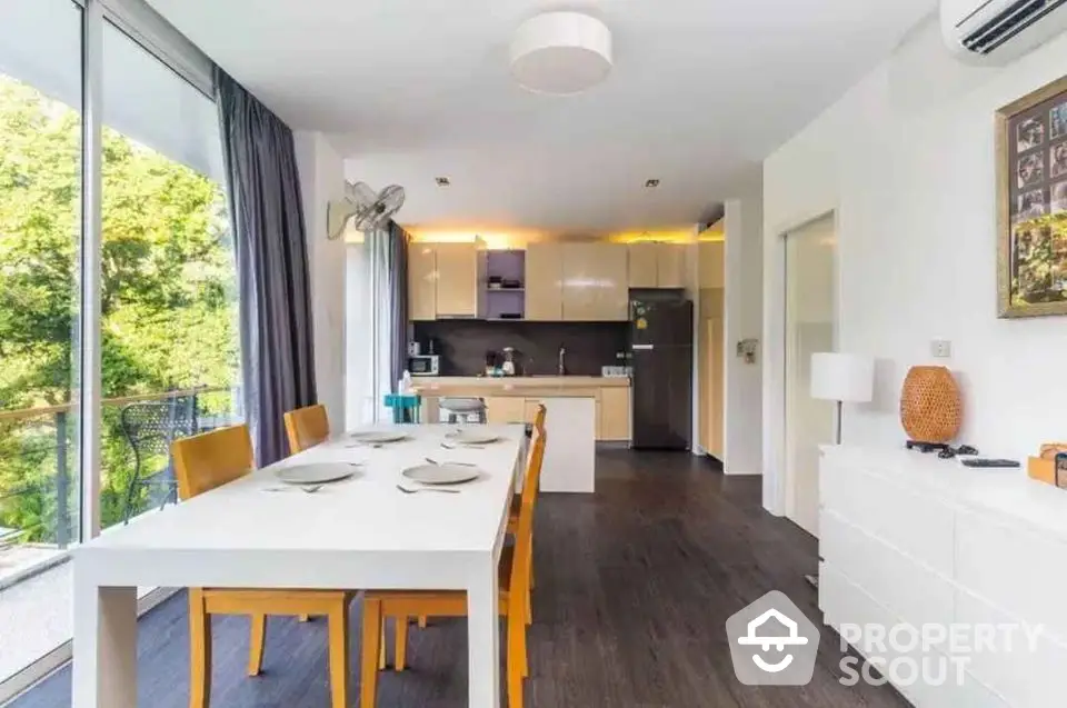 Modern open-layout kitchen and dining area with natural light and balcony view.