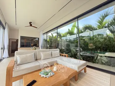 Luxurious living room with modern decor and lush garden view, featuring sleek furniture and expansive glass windows.