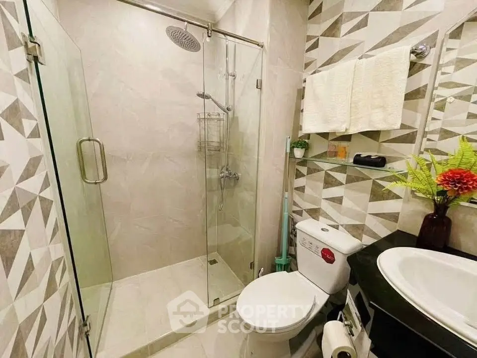 Modern bathroom with glass shower and stylish geometric tiles