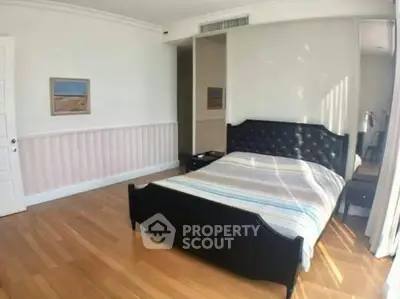 Spacious bedroom with elegant wooden flooring and stylish bed