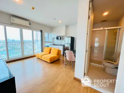 Modern open-plan living room with kitchen, featuring yellow sofa and city view.