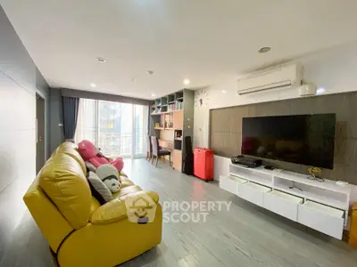 Spacious modern living room with large TV and cozy seating in a stylish apartment.