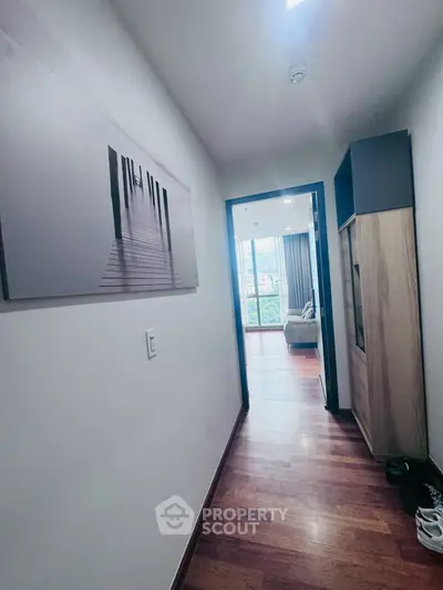 Modern apartment hallway leading to a bright living room with wooden flooring and stylish decor.