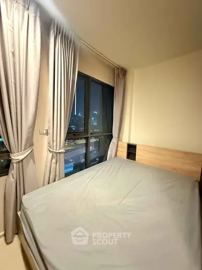 Cozy bedroom with city view, featuring large windows and elegant curtains, perfect for urban living.