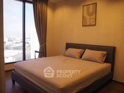 Spacious bedroom with city view and modern decor in high-rise apartment.