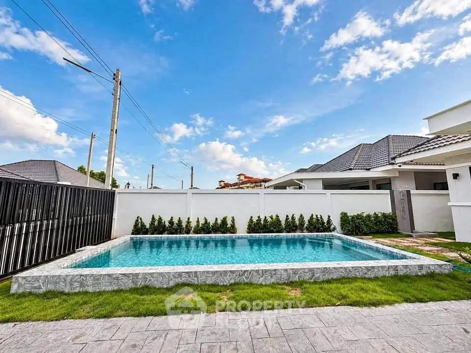 Stunning modern home with private pool and lush landscaping under a clear blue sky.