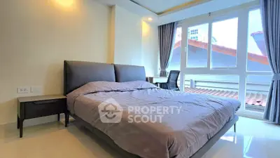 Spacious bedroom with large windows and modern furnishings in a bright apartment.