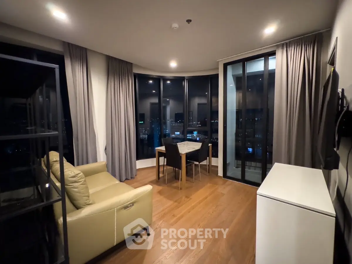 Modern living room with city view, featuring sleek furniture and floor-to-ceiling windows.