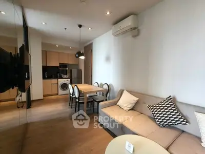 Modern living room with open kitchen, stylish furniture, and wooden flooring in a cozy apartment.