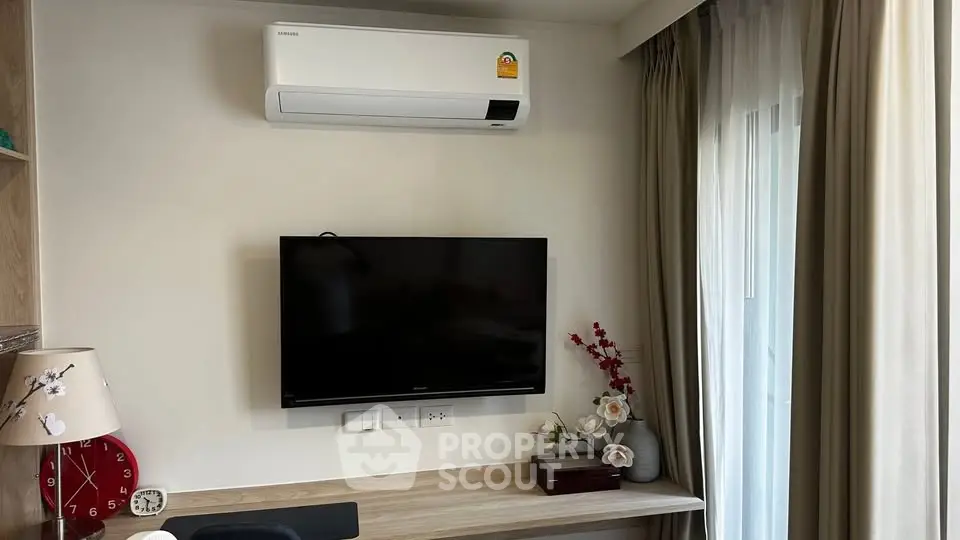 Modern living room with wall-mounted TV and air conditioner, featuring elegant decor and natural light.