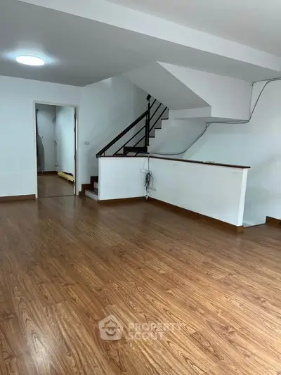 Spacious open-plan living area with wooden flooring and staircase, ideal for modern living.