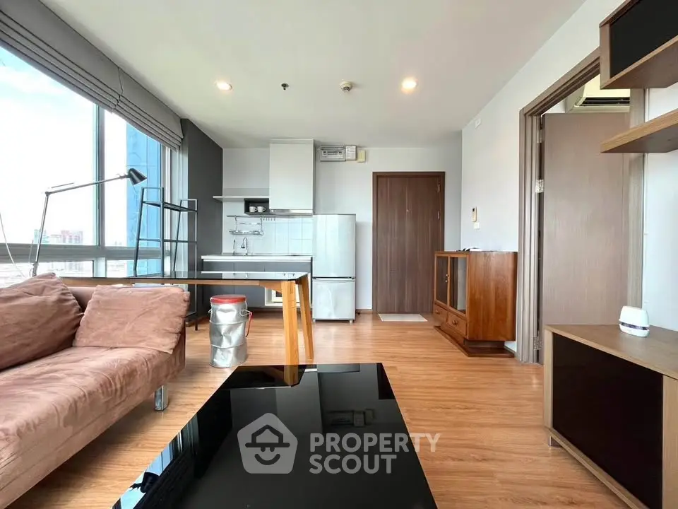 Modern living room with open kitchen, large windows, and stylish furniture in a high-rise apartment.