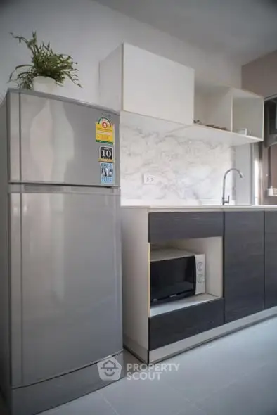Modern kitchen with sleek appliances and marble backsplash in a stylish apartment.