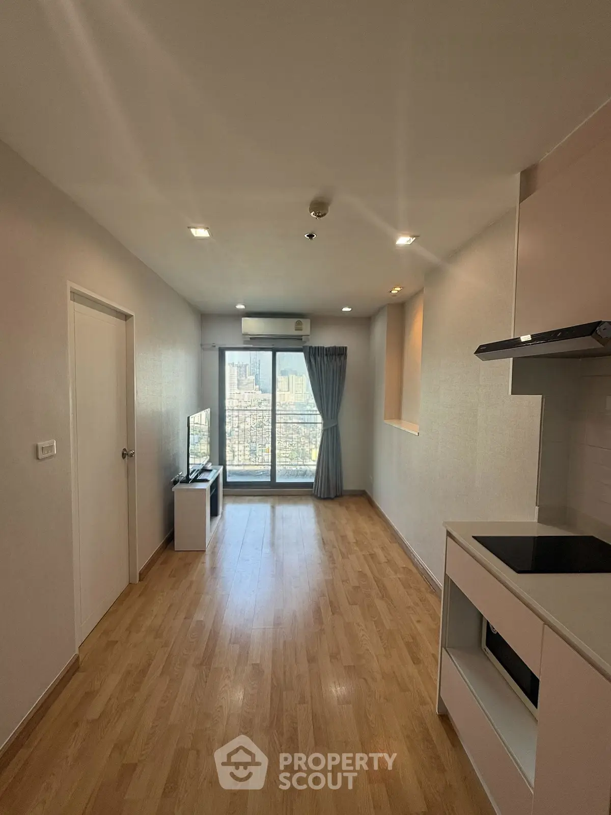 Modern apartment interior with wooden flooring and city view from balcony.