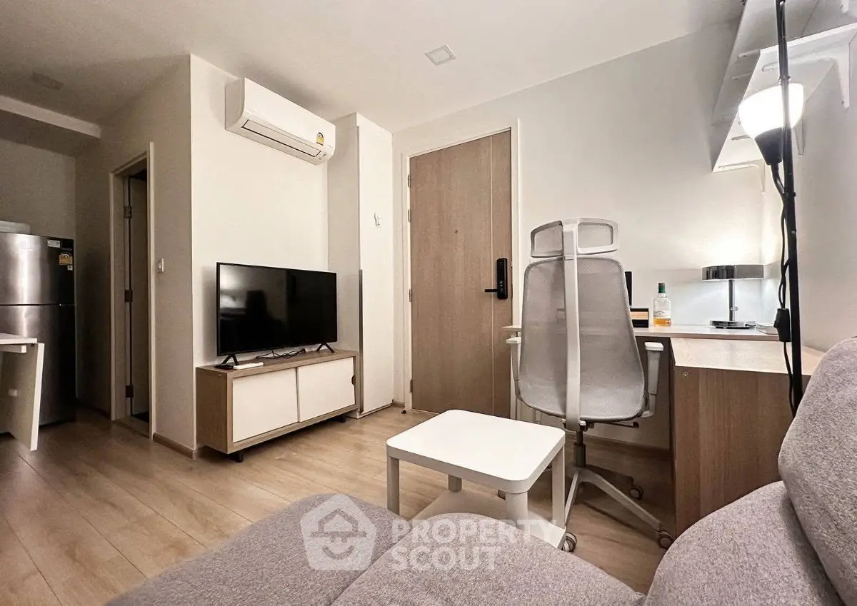 Modern living room with sleek furniture and workspace in a cozy apartment.