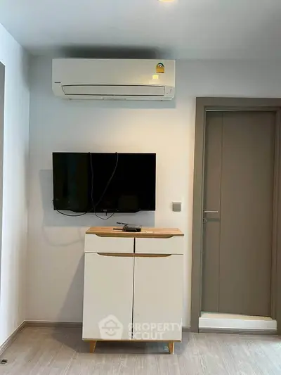 Modern interior with wall-mounted TV and air conditioner above a sleek cabinet.