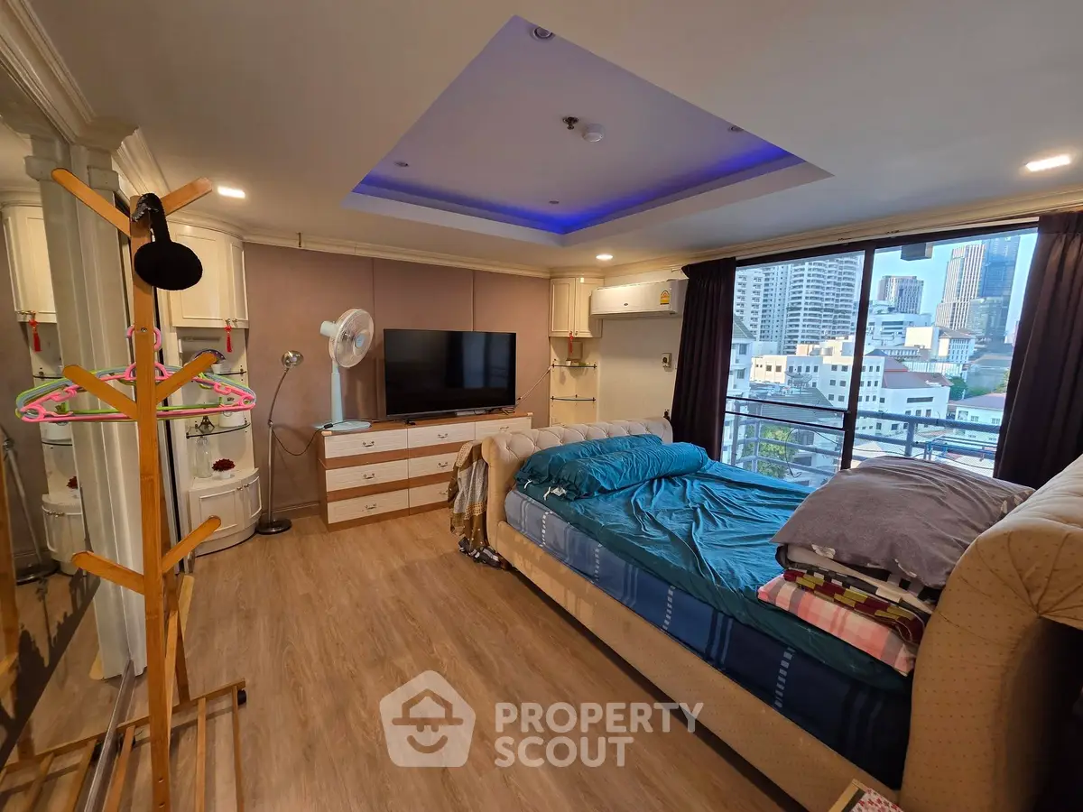 Spacious bedroom with city view, modern decor, and ample natural light