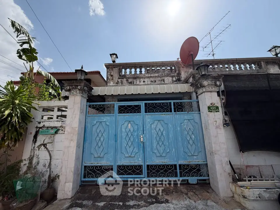 Charming vintage exterior with ornate blue gate and classic architectural details under a clear sky.