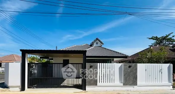Charming single-story home with modern fence and tiled roof under clear blue sky.