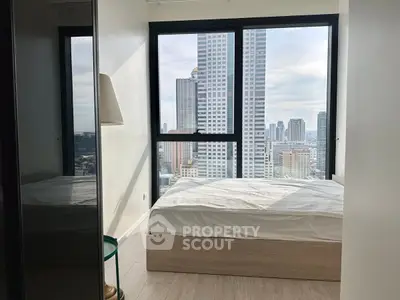 Modern bedroom with stunning city view from large windows in high-rise apartment.