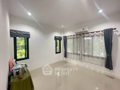 Spacious unfurnished room with large windows and air conditioning, perfect for customization.