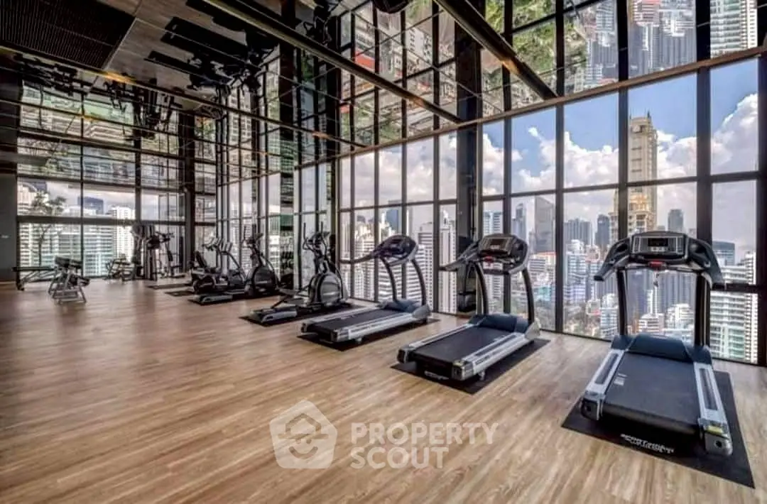 Luxury gym with panoramic city views and modern fitness equipment in high-rise building.