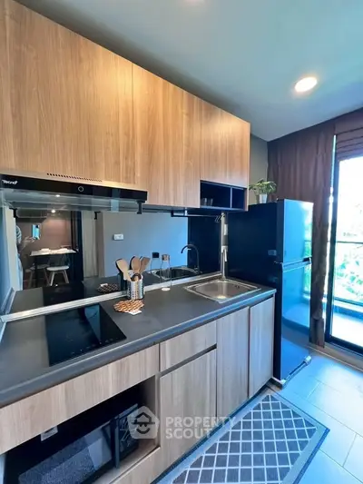 Modern kitchen with sleek wooden cabinets and stainless steel appliances in a stylish apartment.