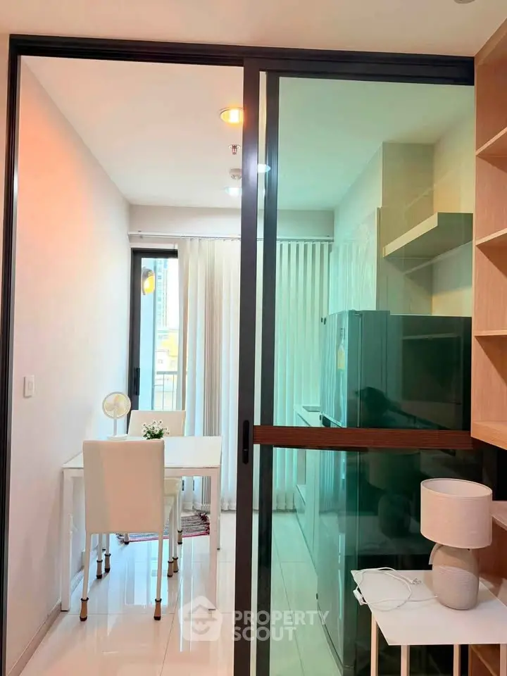 Modern apartment with glass sliding door, compact dining area, and sleek kitchen appliances.