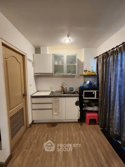 Cozy kitchen with modern cabinets and wooden flooring, perfect for compact living spaces.