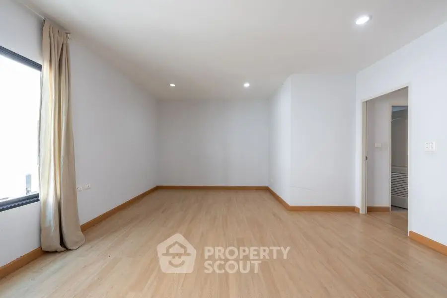 Spacious empty room with wooden flooring and large window