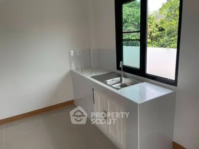 Modern kitchen with sleek countertop and large window overlooking greenery