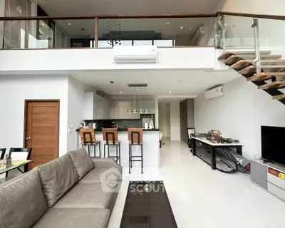 Spacious modern living room with open kitchen and mezzanine, featuring sleek design and ample natural light.