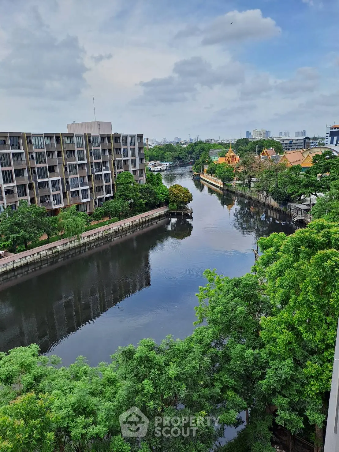 Stunning river view from a high-rise apartment with lush greenery and modern buildings.