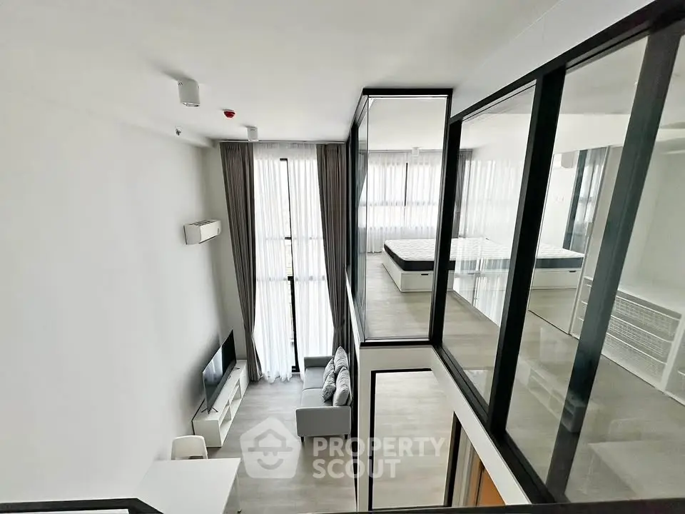 Modern duplex apartment with open living area and bedroom, featuring large windows and minimalist design.