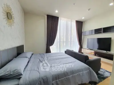 Spacious bedroom with modern decor and large TV, featuring elegant curtains and stylish wall art.