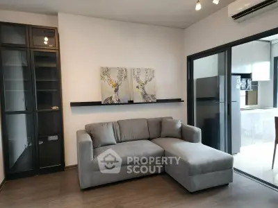 Modern living room with sleek gray sofa and open kitchen layout in stylish apartment.