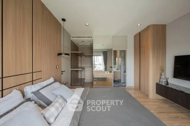 Modern bedroom with stylish decor and ensuite bathroom, featuring wooden accents and a sleek design.