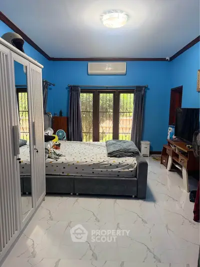 Spacious bedroom with modern decor and large windows for natural light.