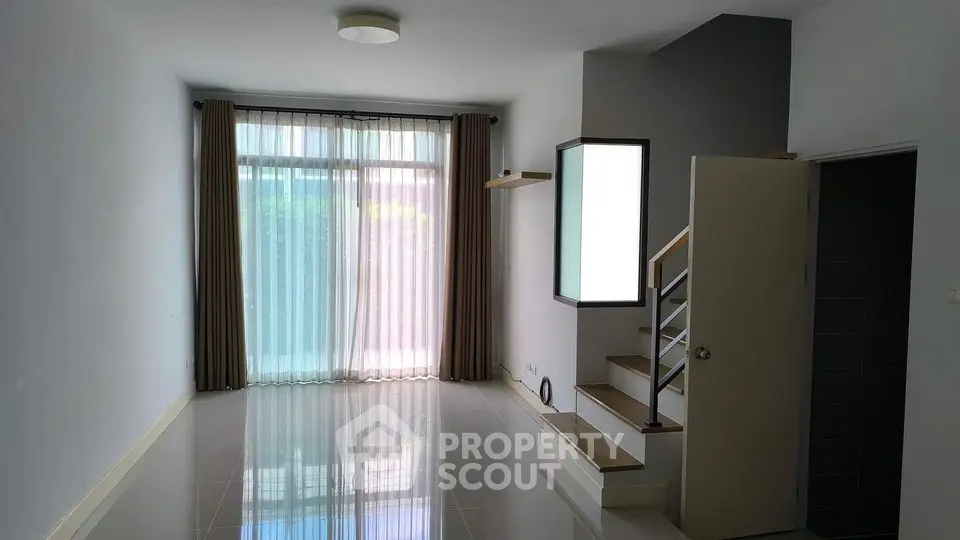 Spacious modern living room with large window and staircase