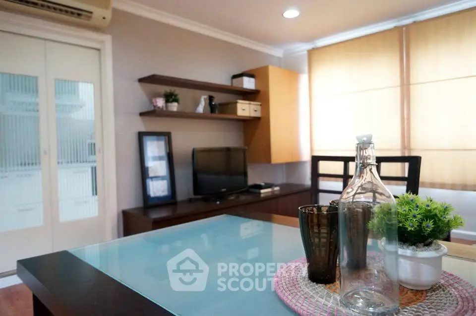 Charming living room with modern decor and natural light, featuring a cozy seating area and stylish shelving.