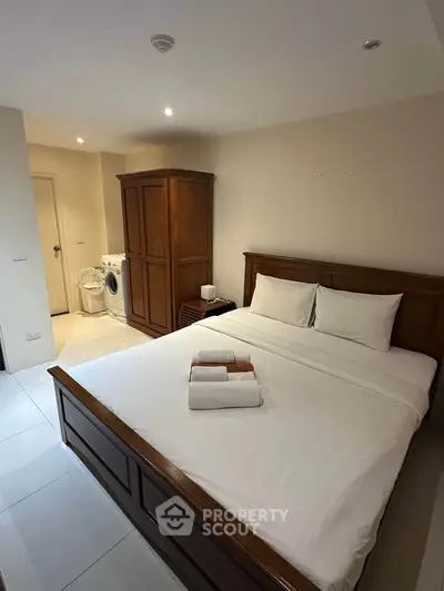 Cozy bedroom with wooden furniture and in-room washing machine, perfect for modern living.