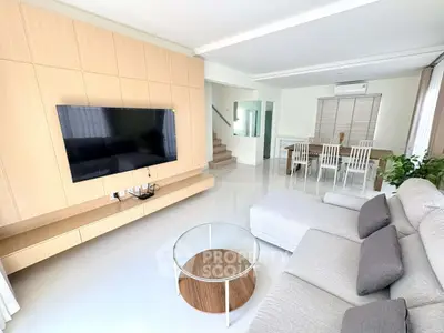 Spacious modern living room with sleek furniture and large TV, perfect for relaxation and entertainment.