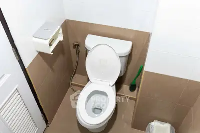 Modern bathroom with toilet and cleaning supplies in a compact layout.