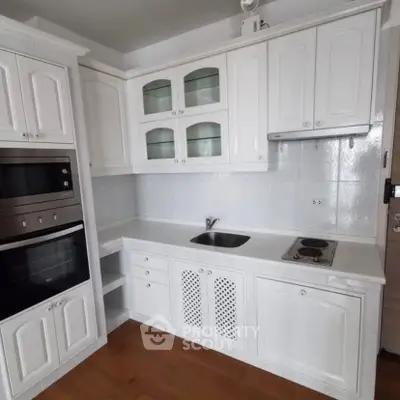 Charming white kitchen with built-in oven and sleek cabinetry, perfect for modern living.