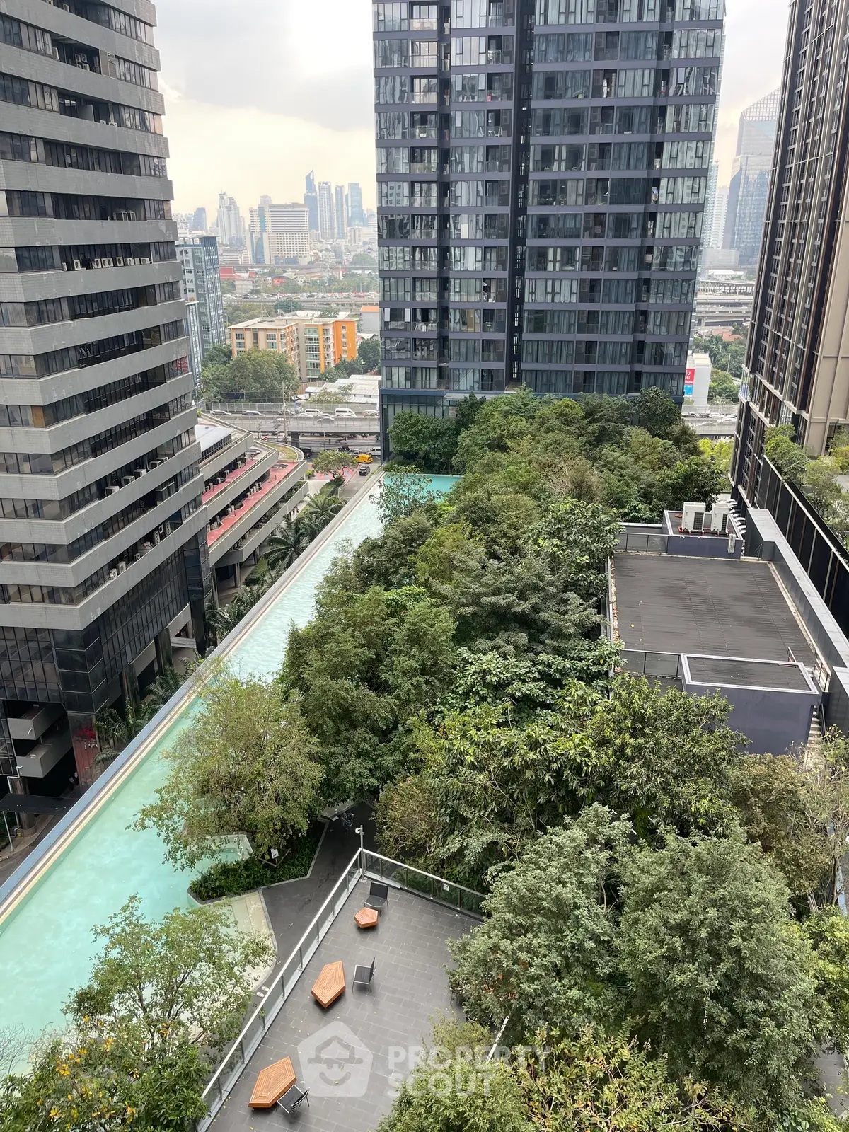 Stunning urban view with lush greenery and modern high-rise buildings, featuring a sleek rooftop pool.