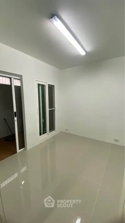 Minimalist room with glossy tiled floor and sliding glass doors, perfect for versatile use.